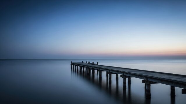 A long wooden pier stretching into calm water at dusk.