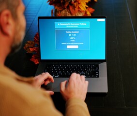 Middle Aged Man Working from Home Takes IT Security Awareness Training from Kitchen Table - Cybersecurity Education for Remote Employees Concept