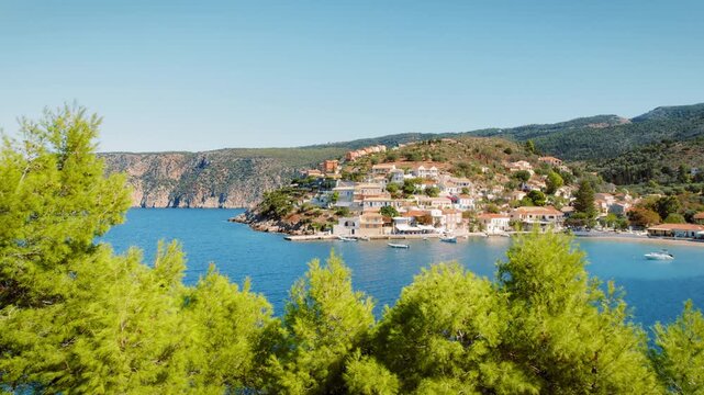 Colorful hillside village Fiscardo by bay with cliffs and pine trees in Kefalonia