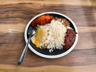 Delicious plate of rice with fried egg and sauces on wooden table