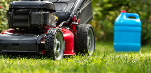 Fototapeta premium A lawnmower sits on a lush green lawn next to a blue fuel container, suggesting routine yard maintenance and the tools required for keeping a well manicured outdoor space during the growing season.