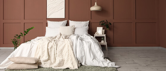 Interior of stylish bedroom with cozy bed, houseplants and painting