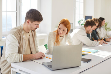 Team of business people or students working and learning together in office, using laptop to foster community collaboration in a professional setting with focus and dedication every day.
