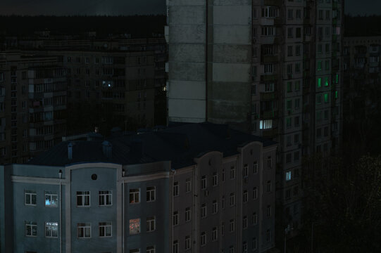 Night view of residential buildings in Ukraine during a blackout, with scarce illuminated windows