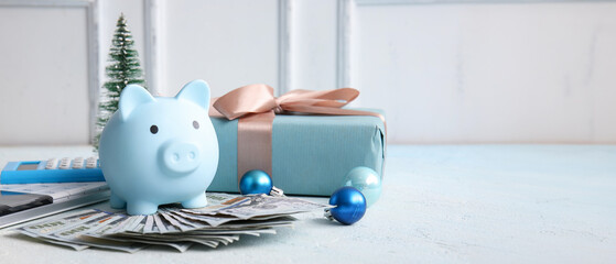 Composition with piggy bank, dollar banknotes, calculators and Christmas gift on light table