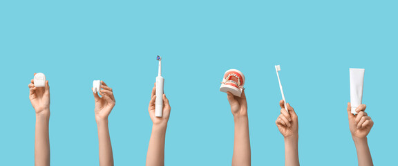 Female hands with dental models and oral hygiene supplies on blue background