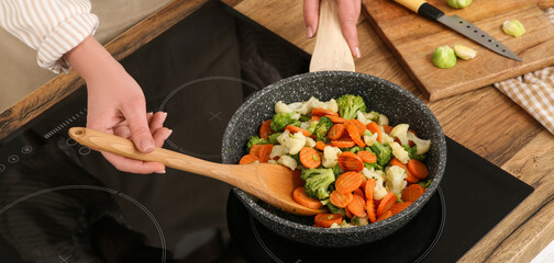 Young woman roasting tasty vegetables in kitchen
