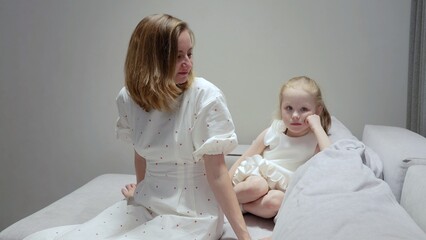 Loving mother comforting crying child on cozy living room sofa, showing gentle support during emotional moment between parent and kid