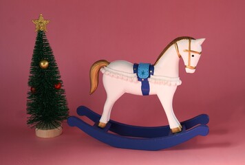 Vintage White Rocking Horse Figurine Near Christmas Tree on Red Background as 2026 Symbol as Greeting Card Concept