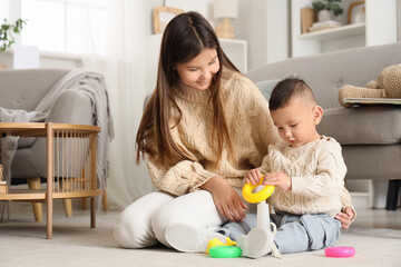 Teenage girl and her little brother playing with toy pyramid at home