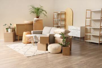 Interior of living room with grey sofa and cardboard boxes on moving day
