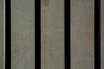 Close up vertical gray metal bars with rust texture and dark gaps, industrial steel background.
