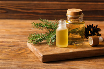 Bottles with coniferous cone essential oil on wooden background