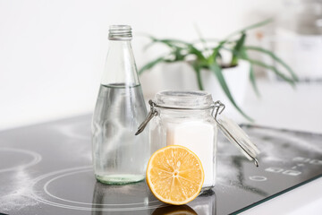 Lemon with baking soda and vinegar on stove in kitchen, closeup