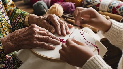 Two people hands doing embroidery with craft supplies and yarn in the background - Powered by Adobe