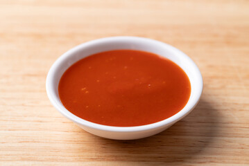 Sriracha sauce in a bowl on wooden background, Chili sauce
