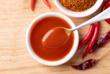 Sriracha sauce in a bowl with spoon on wooden background, Chili sauce, Table top view