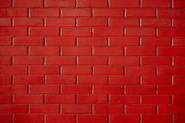 Bright red painted brick wall texture, vibrant colorful background pattern for design.