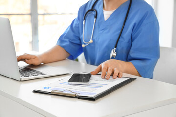 Female doctor working with laptop at desk in office, closeup