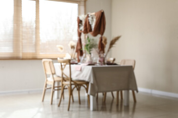 Blurred view of elegant table setting with beautiful flowers and draped fabric decor in stylish dining room