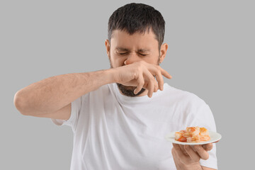 Young man with runny nose and shrimps on light background. Food Allergy Awareness Month