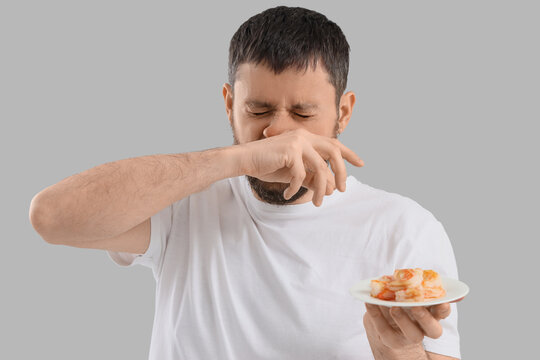 Young man with runny nose and shrimps on light background. Food Allergy Awareness Month
