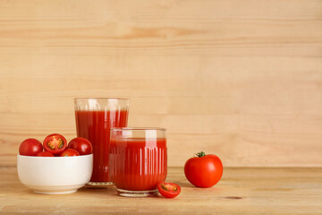 Glasses of fresh tomato juice and vegetables on wooden background