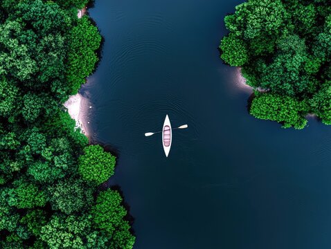 An aerial view shows a white canoe with a paddle on a dark blue lake, bordered by vibrant green trees.