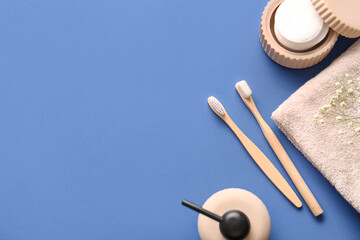 Bamboo toothbrushes with cotton pads and towel on blue background