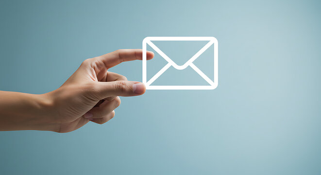 Hand holding a glowing white email icon against a light blue background, symbolizing communication.
