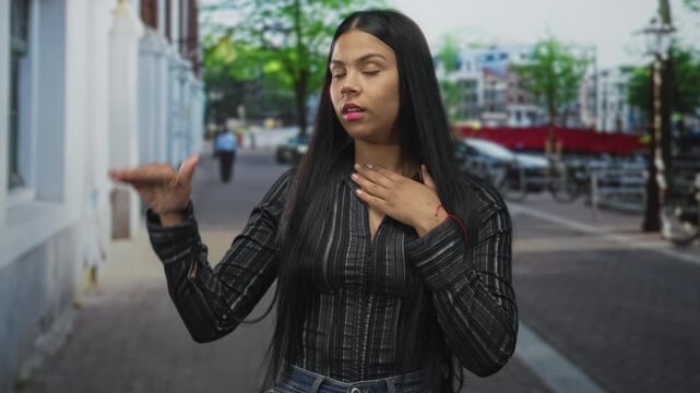 Woman raises right hand and presses left hand to chest on street with focused expression; honesty promise.
