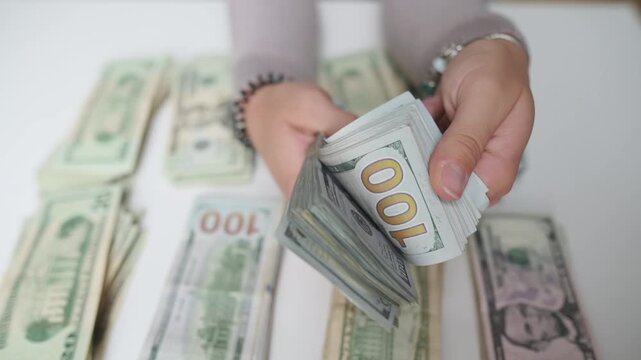 woman counts cash meticulously, female doing precise cash counting on tidy banking surface, woman meticulously handling stacks of currency preparing for banking transaction