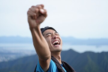 Triumphant male hiker raises fist in exultation on a mountain peak