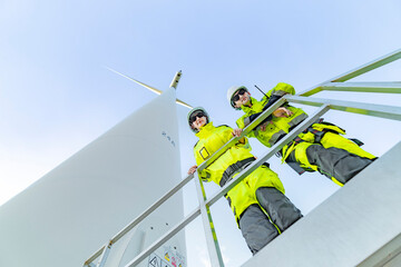 Team of engineers in reflective work suits join hands to inspect and demonstrate their work and...