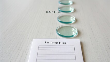 Transparent lenses arranged on a surface with motivational phrases highlighting personal growth and discipline for self-improvement