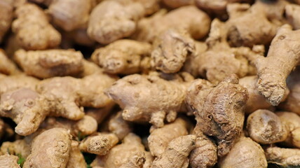Pile of fresh ginger root displayed at a market stall, showcasing its knobby texture and earthy tones, creating a warm and inviting atmosphere.