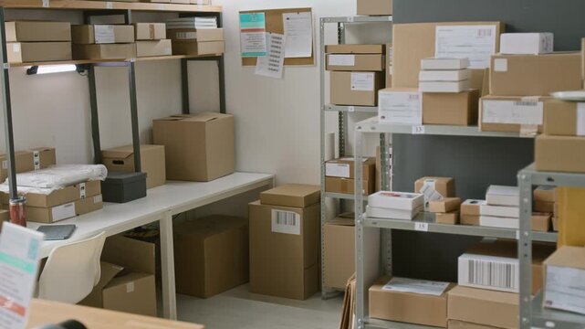 Full no people shot of racks and shelves with assorted cardboard parcels and packages with barcodes at courier delivery office company, prepared for shipment