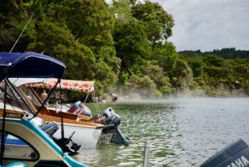 Geothermal hot water beach with pleasure boats on Lake Tarawera New Zealand