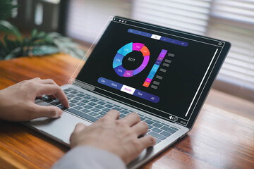 Hands working on a laptop displaying a colorful data analytics dashboard, featuring charts and metrics for business insights, productivity monitoring, digital reporting.