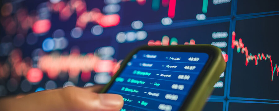 Analyzing stock market data on a smartphone with charts in the background