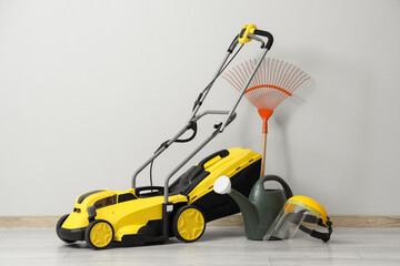 Fototapeta premium Lawn mower with gardening tools near light wall in room