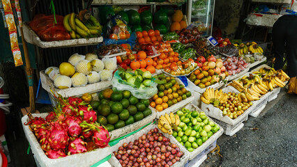 Vibrant fruit stall overflowing with bananas, dragon fruit, oranges, limes, and more. Fresh produce...
