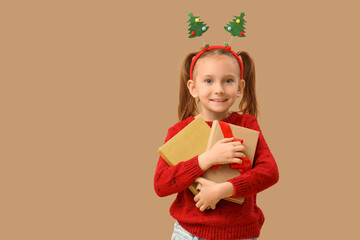 Naklejka premium Cute little girl with books on beige background. Christmas celebration