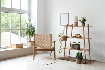 Interior of light room with wooden armchair, shelf unit and plants
