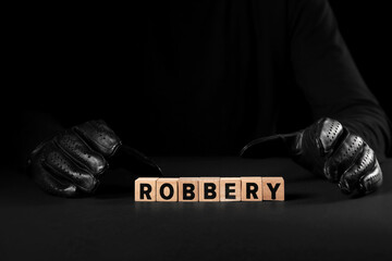 Thief with word ROBBERY at black table, closeup