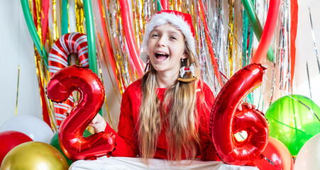Young girl celebrating new year with red number balloons indoors