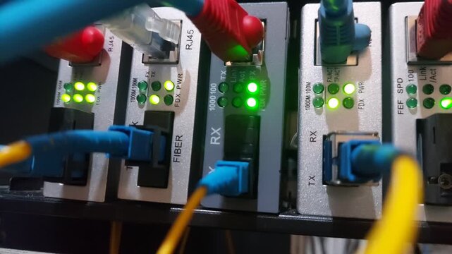Close-up footage of a UTP network cable being plugged into a router switch port with green LED indicators blinking, showing active data connection and modern networking infrastructure.