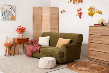 Interior of living room with autumn leaves, sofa and folding screen