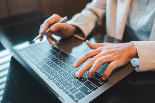 Close-up of hands typing on a laptop and writing notes, symbolizing productivity and modern business practices.