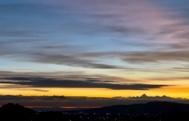 Vibrant Sunset Over City Lights with Mountain Silhouette